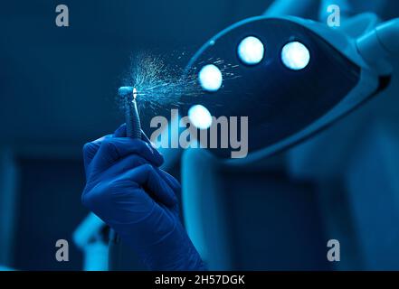 Nahaufnahme der Zahnbohrmaschine mit Spritzwasser vor dem Hintergrund der mitgelieferten Lampe Licht in Zahnarztpraxis . Zahnmedizin, Zahnarztpraxis, maxil Stockfoto