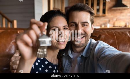 Glückliche Millennial Ehegatten neue Hauskäufer schießen Selfie mit Schlüsseln Stockfoto