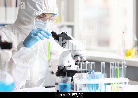 Wissenschaftler Chemiker in Schutzanzug hält Reagenzglas mit grüner Flüssigkeit im Labor Stockfoto