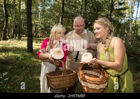 Drei Pilzsammler trafen sich im Wald und schauen auf ihre Pilze. Macrolepiota procera. Stockfoto