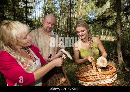 Drei Pilzsammler trafen sich im Wald und schauen auf ihre Pilze. Macrolepiota procera. Stockfoto