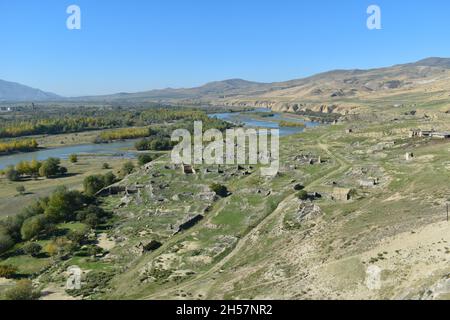 Blick auf den Fluss Mtkvari oder den Fluss Kura von der Felshöhle Uplistsikhe in Georgien, Asien. Flussufer mit Herbstbäumen und Hügeln im Hintergrund Stockfoto