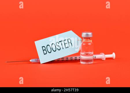 Konzept für die Corina-Virus-Booster-Impfung mit Fläschchen und Spritze auf rotem Hintergrund Stockfoto