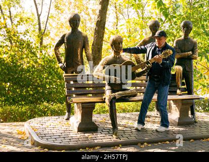 Tourist posiert mit den Beatles, Liverpool vier Statuen auf dem Gelände des Kok-Tobe Berges in Almaty, Kasachstan, Zentralasien Stockfoto