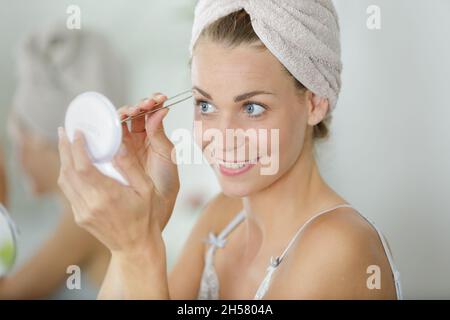 Frau Zupfen der Augenbrauen mit Pinzette Stockfoto