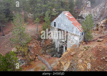 Verlassene Chromit-Mine im Troodos-Gebirge, Zypern. Alte kaputte Aufzug über vertikalen Schacht von Pinien umgeben Stockfoto