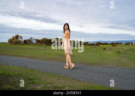 Junge asiatische Frau, die mit Gänsen läuft Stockfoto