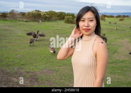 Junge asiatische Frau, die mit Gänsen läuft Stockfoto