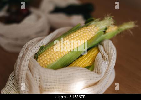 Frischer roher Mais in Öko-Canvas-Lebensmittelbeutel. Baumwollbeutel auf Holztisch. Zero Waste Shopping-Konzept. Kunststoffartikel Stockfoto