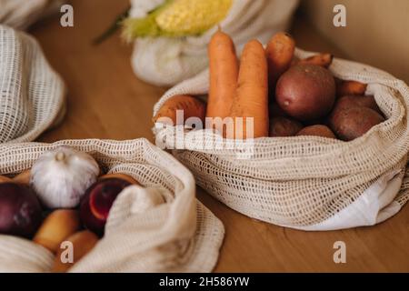 Karotten und Kartoffeln Leinwand Lebensmittelbeutel. Gemüse in wiederverwendbaren Öko-Baumwollbeuteln auf Holztisch. Zero Waste Shopping-Konzept. Kunststoffartikel Stockfoto