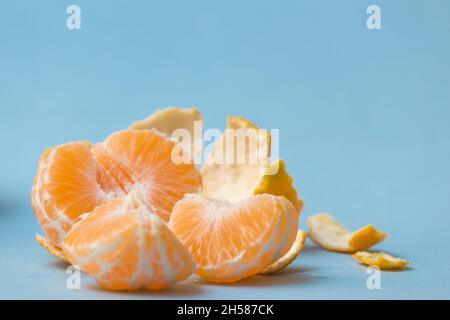 mandarine geschält und in Segmente unterteilt, auf blauem Hintergrund, gesunde Zitrusfrüchte Stockfoto