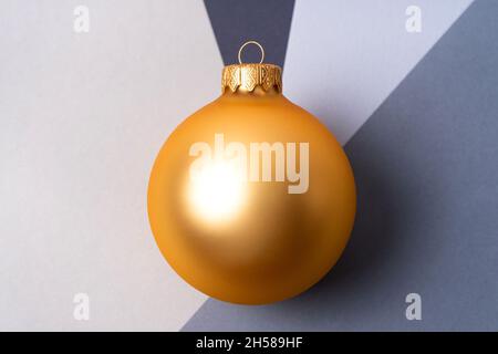 Goldene Weihnachtskugel an der Kreuzung von vier Grautönen. Weihnachts- und Neujahrskonzept Stockfoto