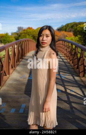 Junge asiatische Frau in einem Kleid auf einer Metall- und Holzbrücke in den Sümpfen Stockfoto