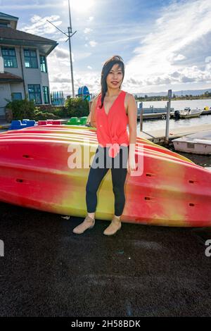 Junge asiatische Frau, die an einem See um ein Bootshaus herumläuft Stockfoto