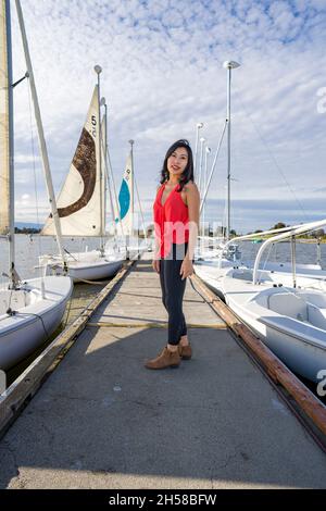 Junge asiatische Frau, die an einem See um ein Bootshaus herumläuft Stockfoto