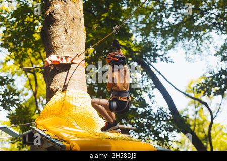 Das konzentrierte Mädchen überwindet sorgfältig Hindernisse im Seilpark Stockfoto