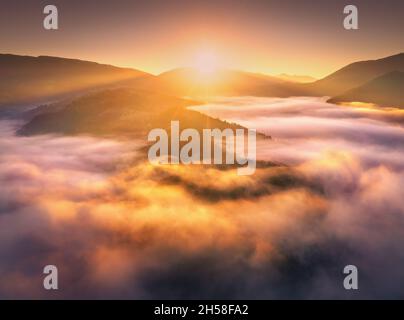 Berge in niedrigen Wolken bei Sonnenaufgang im Sommer. Luftaufnahme Stockfoto