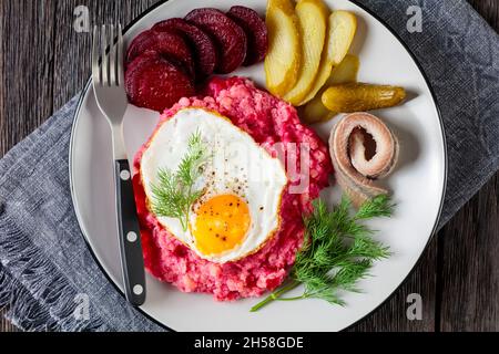 labskaus, Corned Beef, Kartoffelpüree mit Rote Bete und Spiegeleiern, in Scheiben geschnittene Rüben, Gurken und Hering auf einem Teller, hamburgs Stockfoto