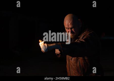 Der kahlköpfige Kaukasusmann schlägt mit brennender Faust. Stockfoto