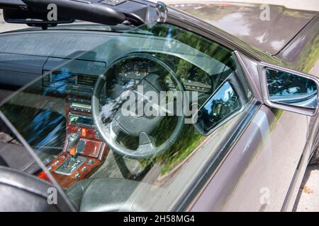 Lenkrad und Armaturenbrett eines Mercedes Benz SL320 durch Spiegelungen im Autofenster betrachtet Stockfoto