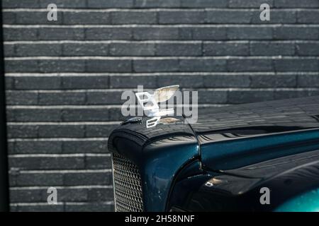 Kühlerfigur Flying B des Green Bentley Brooklands, geparkt an einer schwarzen Lagerhauswand Stockfoto