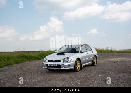 Silver 2001 Subaru WRX XTI mit goldenen Rädern auf Schotter neben Moorland im Peak District Stockfoto