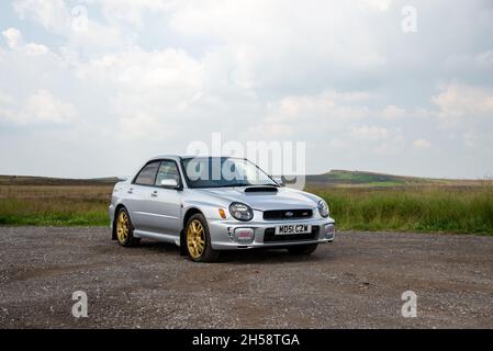 Silver 2001 Subaru WRX XTI mit goldenen Rädern auf Schotter neben Moorland im Peak District Stockfoto