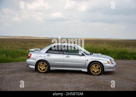 Silver 2001 Subaru WRX XTI mit goldenen Rädern auf Schotter neben Moorland im Peak District Stockfoto