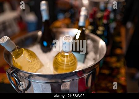 Weißwein wird in einem Eiskübel zusammen mit Rotwein auf dem Tisch gekühlt Stockfoto