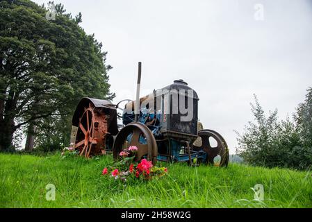 Vintage Fordson Traktor steht auf Gras auf einer Wiese mit Blumen um ihn herum Stockfoto