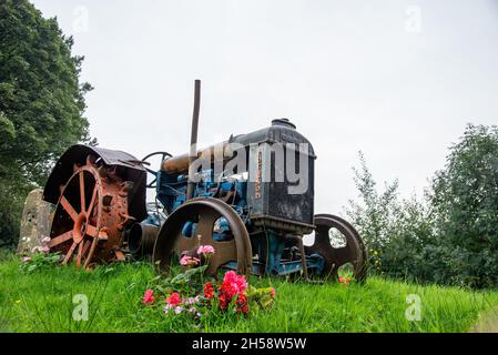 Vintage Fordson Traktor steht auf Gras auf einer Wiese mit Blumen um ihn herum Stockfoto