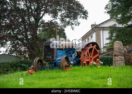 Vintage Fordson Traktor steht auf Gras auf einer Wiese mit Blumen um ihn herum Stockfoto