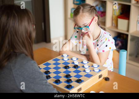 Mädchen mit Down-Syndrom spielt mit ihrer Schwester in Quarantäne Checkers Stockfoto