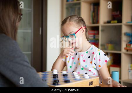 Mädchen mit Down-Syndrom spielt mit ihrer Schwester in Quarantäne Checkers Stockfoto