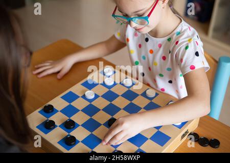 Mädchen mit Down-Syndrom spielt mit ihrer Schwester in Quarantäne Checkers Stockfoto