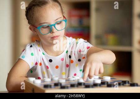 Mädchen mit Down-Syndrom spielt mit ihrer Schwester in Quarantäne Checkers Stockfoto