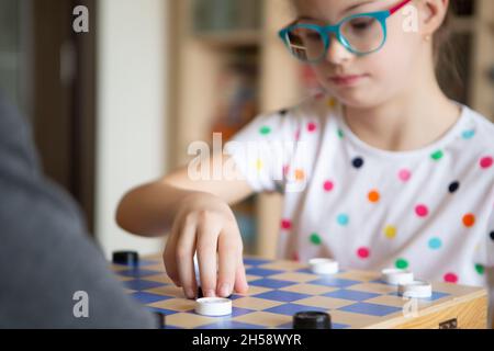 Mädchen mit Down-Syndrom spielt mit ihrer Schwester in Quarantäne Checkers Stockfoto