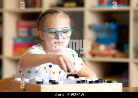 Mädchen mit Down-Syndrom spielt mit ihrer Schwester in Quarantäne Checkers Stockfoto