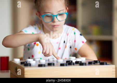 Mädchen mit Down-Syndrom spielt mit ihrer Schwester in Quarantäne Checkers Stockfoto