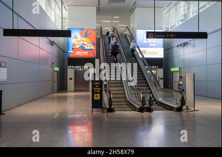 06/09/2021. Stansted Airport, Großbritannien. Ein paar Passagiere mit Handgepäck auf Rolltreppen, die in Richtung Abfluggate fahren. Stockfoto