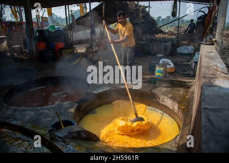 Roorkee, Indien. November 2021. Ein Arbeiter rührt heißen und dicken Zuckerrohrsaft in der Produktionseinheit von Jaggery im unteren Teil von Roorkee.die Herstellung von Zuckerrohrsaft ist in vielen Teilen Indiens eine traditionelle ländliche Industrie. Mehr als 70 % der weltweiten Produktion von Jaggery werden von Indien produziert. Kredit: SOPA Images Limited/Alamy Live Nachrichten Stockfoto