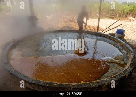 Roorkee, Indien. November 2021. Ein Arbeiter rührt heißen und dicken Zuckerrohrsaft in der Produktionseinheit von Jaggery im unteren Teil von Roorkee.die Herstellung von Zuckerrohrsaft ist in vielen Teilen Indiens eine traditionelle ländliche Industrie. Mehr als 70 % der weltweiten Produktion von Jaggery werden von Indien produziert. Kredit: SOPA Images Limited/Alamy Live Nachrichten Stockfoto