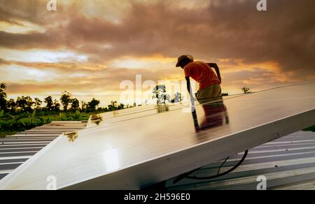 Mann überprüft Solarpanel auf dem Dach auf Sicherheit. Wartung von Solarmodulen oder Photovoltaikmodulen. Nachhaltige Ressourcen und erneuerbare Energien. Solarstrom Stockfoto