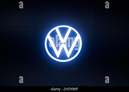 Leuchtendes rundes volkswagen-Logo an der weißen Gebäudewand bei nebliger Nacht Stockfoto