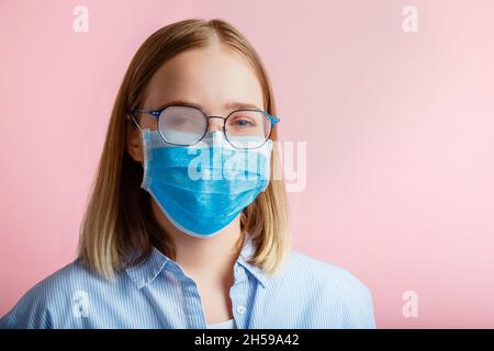 Neblige Brille trägt auf Frau. Frau Porträt in medizinischen Schutz Gesichtsmaske und Brillen wischt verschwommen neblig vernebelte Gläser auf rosa Farbe Stockfoto