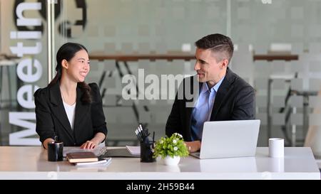 Glückliche Geschäftskollegen bei einem kleinen Meeting in einem modernen Konferenzraum. Vielfältige Mitarbeiter. Stockfoto