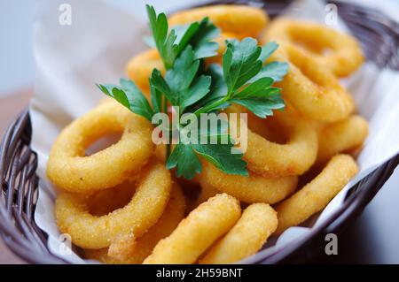 Goldene Farbe tief gebrannt knusprigen Zwiebelring Calamari Ringe mit Koriander Fast Food Nahaufnahme Ansicht Stockfoto