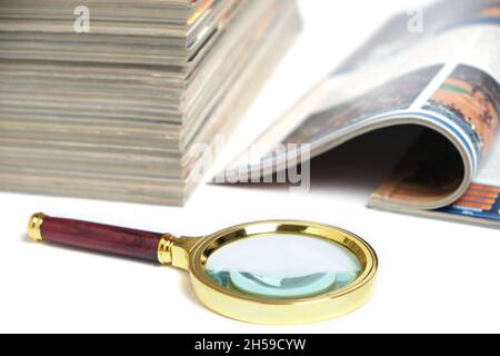 Stapel von Zeitschriften und Lupe auf weißem Hintergrund.Konzept des Lernens und der Verfolgung von Wissen Stockfoto