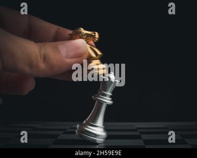 Nahaufnahme Pferd, goldener Ritter Schach Stück greifen die silberne Königin auf Schachbrett auf dunklem Hintergrund. Handbewegende Schachfigur auf Schachspiel-Wettbewerb Stockfoto