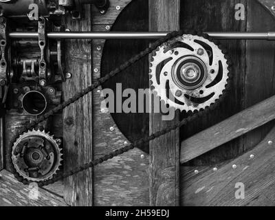 Alte rostige Zahnräder auf Holzhintergrund, schwarz-weiß Stil angeordnet. Gemischt und passen Sie den Hintergrund mit Zahnrädern, Fahrradkette, Maschinen auf vint Stockfoto